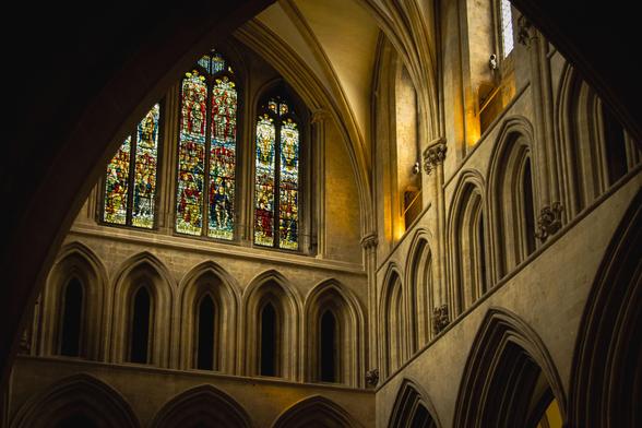 Interior of Wells Cathedral: stained-glass window and arches in the transept.