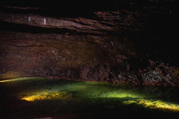 View inside the cave. Spotlights light up the rock formations and an underground river.
