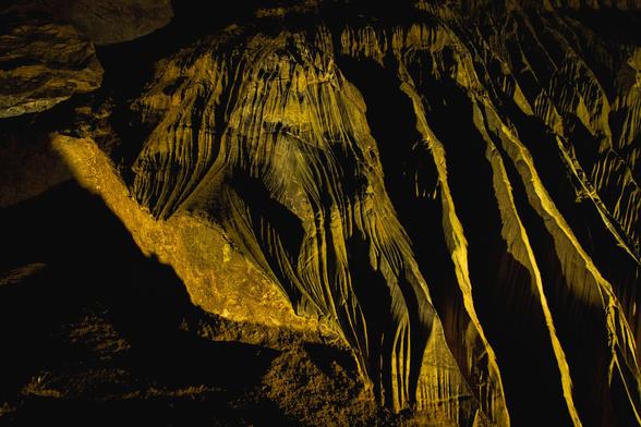 Interior view of a cave: rock formations with sharp ridges bathed in yellow light.