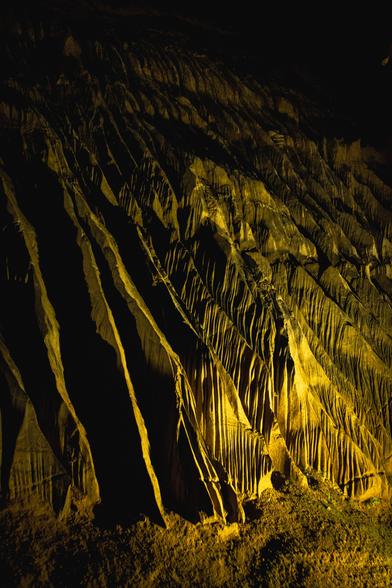 Interior view of a cave: rock formations with sharp ridges bathed in yellow light.