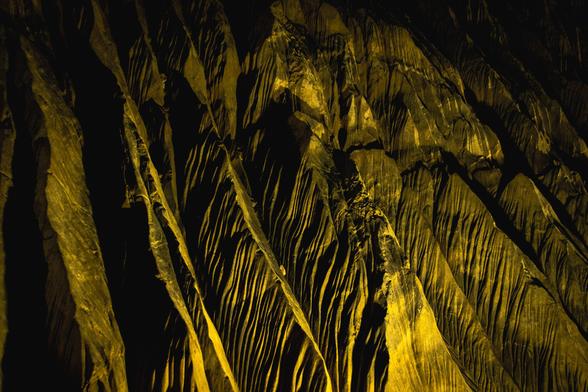 Interior view of a cave: rock formations with sharp ridges bathed in yellow light.