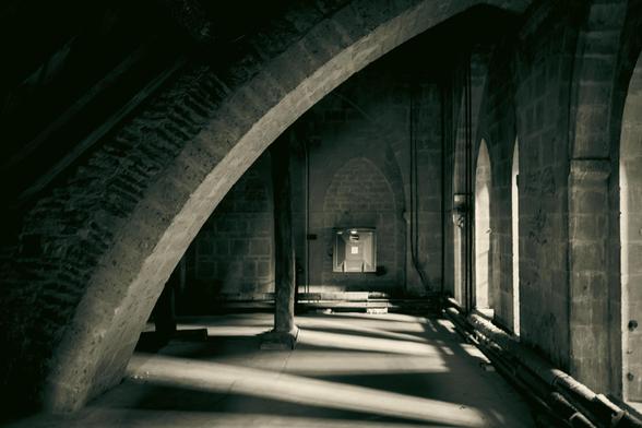 Space underneath the cathedral roof: a large stone arch on the left and windows on the right.