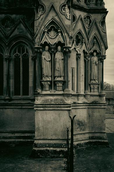 A detail of the Cathedral's facade, looking at the corner of the building, with arches and religious statues in black and white.