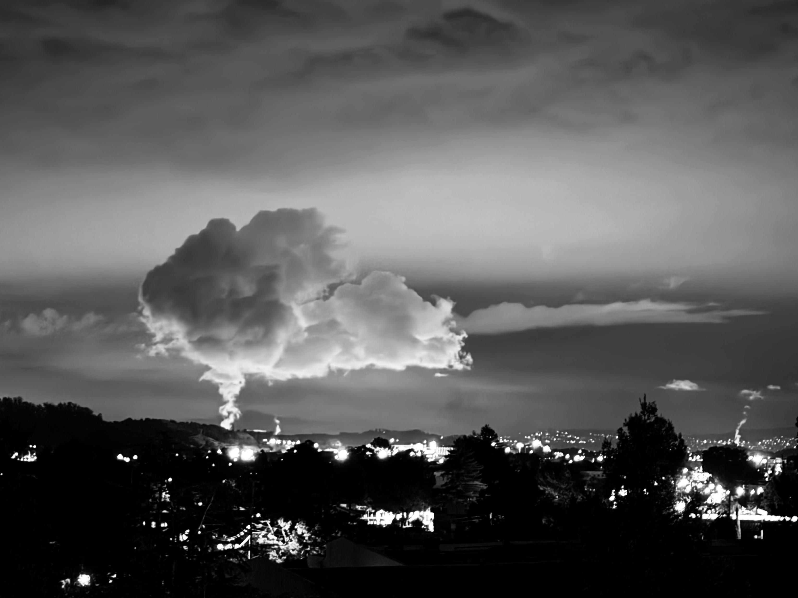 a large cloud rising up into the night sky from the chevron oil refinery