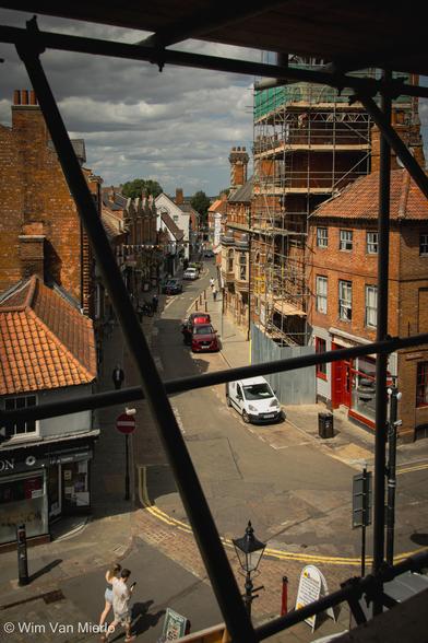 View down into a quiet street from behind scaffolding.