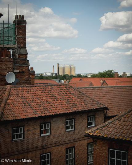 View across the rooftops towards the silos under a blue sky.