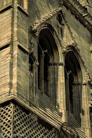 A closely-cropped detail of the church spire showing two arched windows in the sunight.