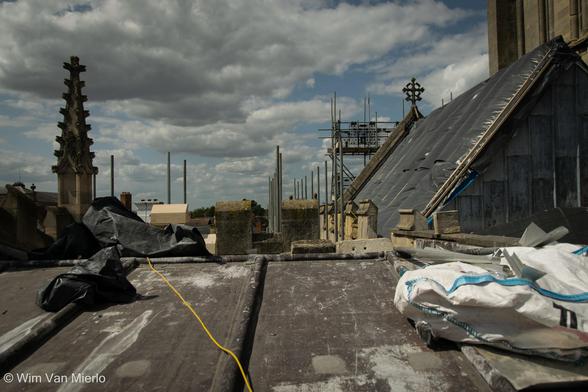 The rooftop of the church during construction work in the sunlight and with a sky full of white-grey clouds.