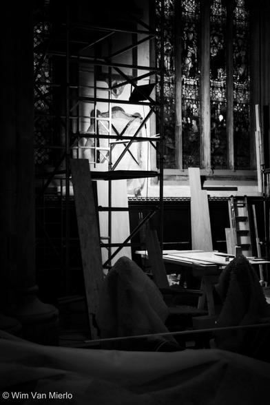 Black and white of the church during construction. Scaffolding next to the stained-glass windows. Strong shadows.