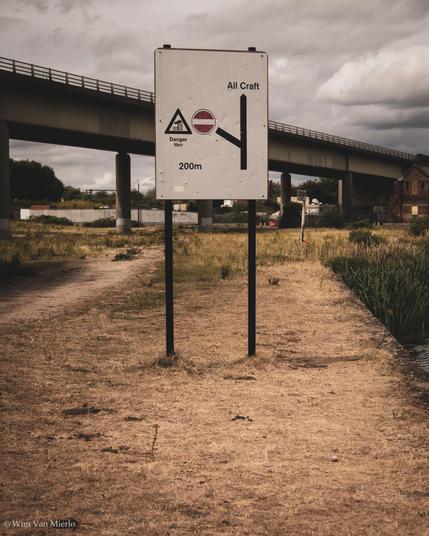 A large traffic sign for river/boat traffic in the foreground; a concrete viaduct carries an A road across a river, which is out of sight.