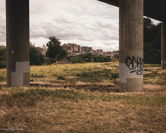 Looking underneath a concrete viaduct towards the houses on the edge of town.