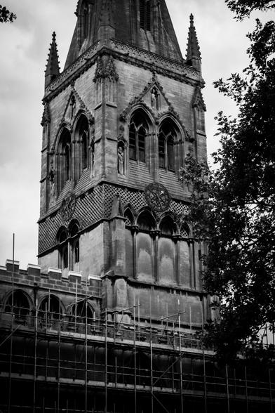 Black and white image with a section of the church spire; the bottom is covered in scaffoldin