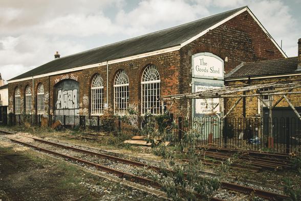Photograph of an old brick-building with a painted sign reading "The Good Shed" alongside a disused railway siding.