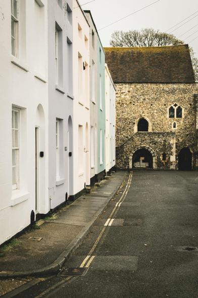 Photograph of a view along a quiet street with a historic church or chapel at the bottom.