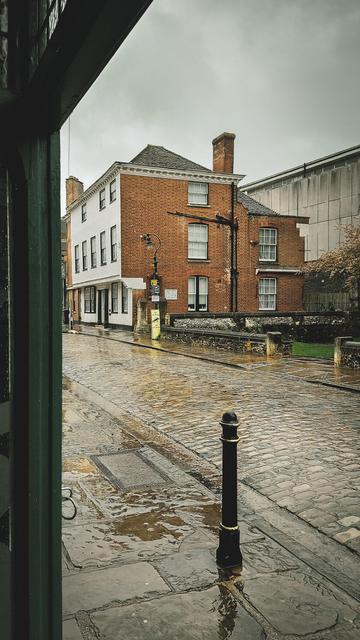 A view of a street in the rain from inside a door frame.